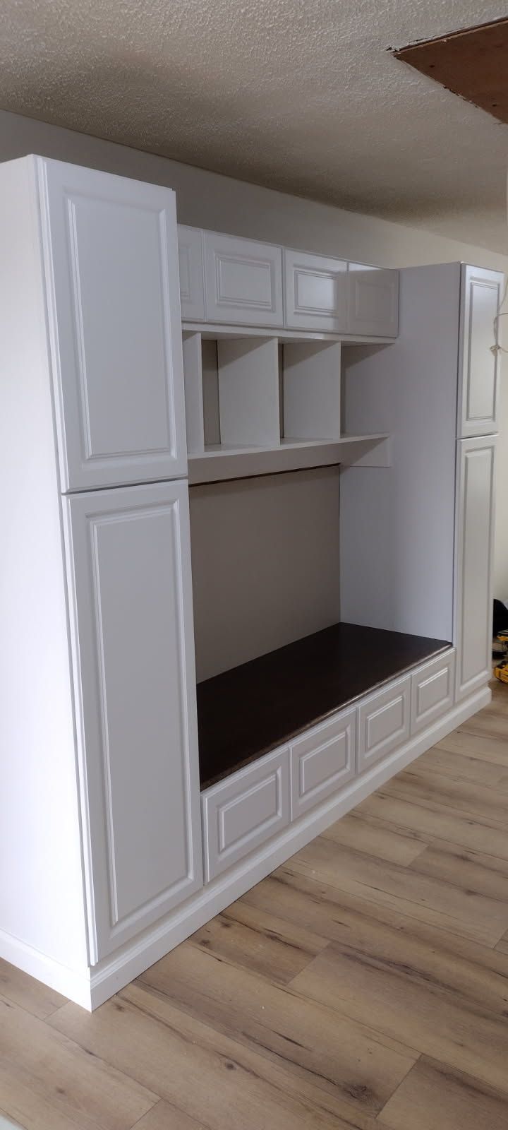 A room with a lot of white cabinets and a wooden floor.