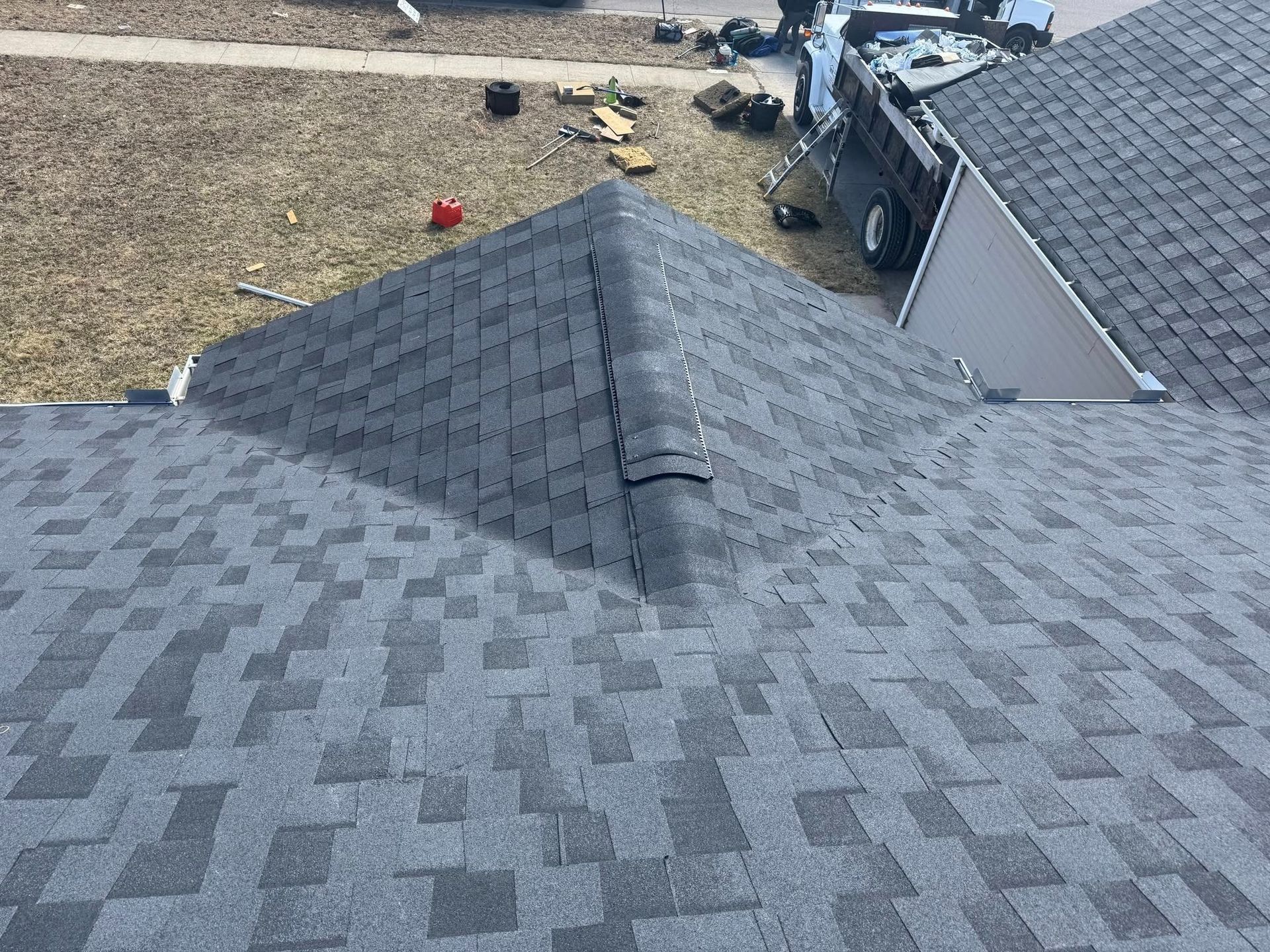 A roof is being installed on a house with a truck parked in the background.