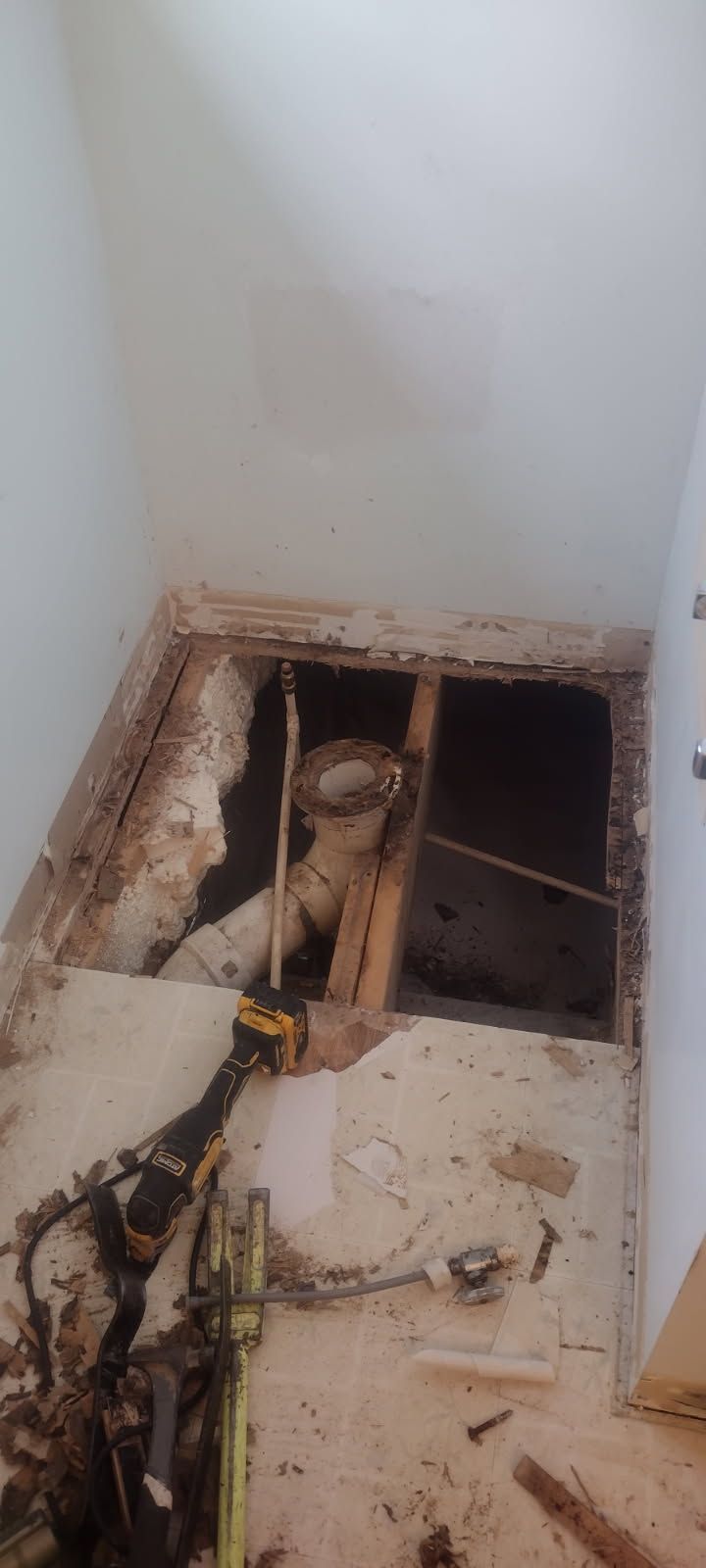 A hole in the floor of a bathroom with a toilet in it.