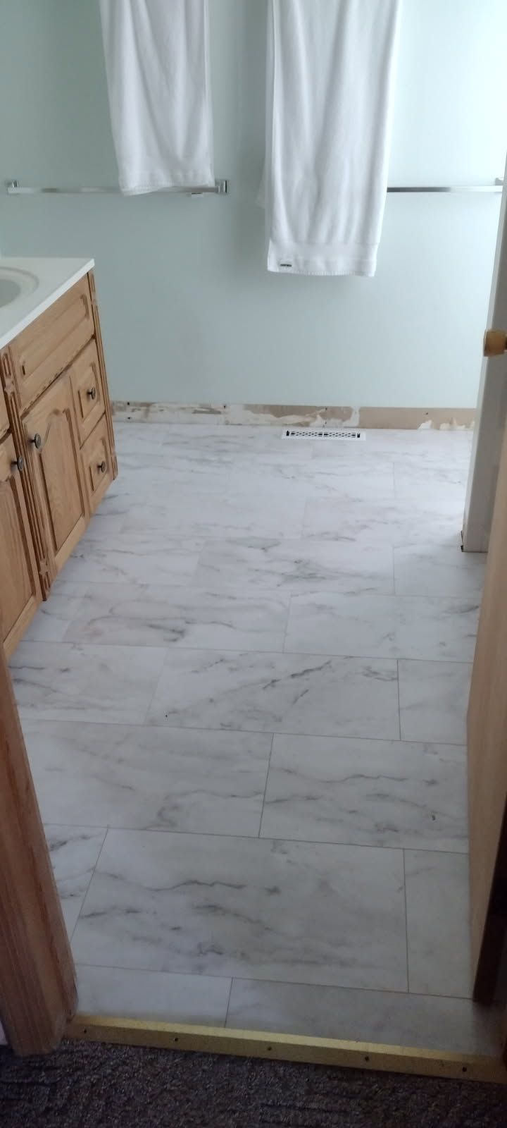 A bathroom with a white tile floor and two towels on the wall.