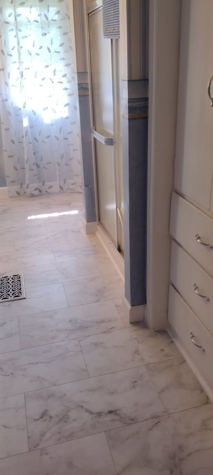 A hallway in a house with a marble floor and a refrigerator.