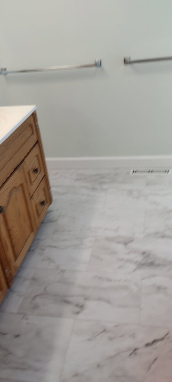 A bathroom with a wooden vanity and marble floor.