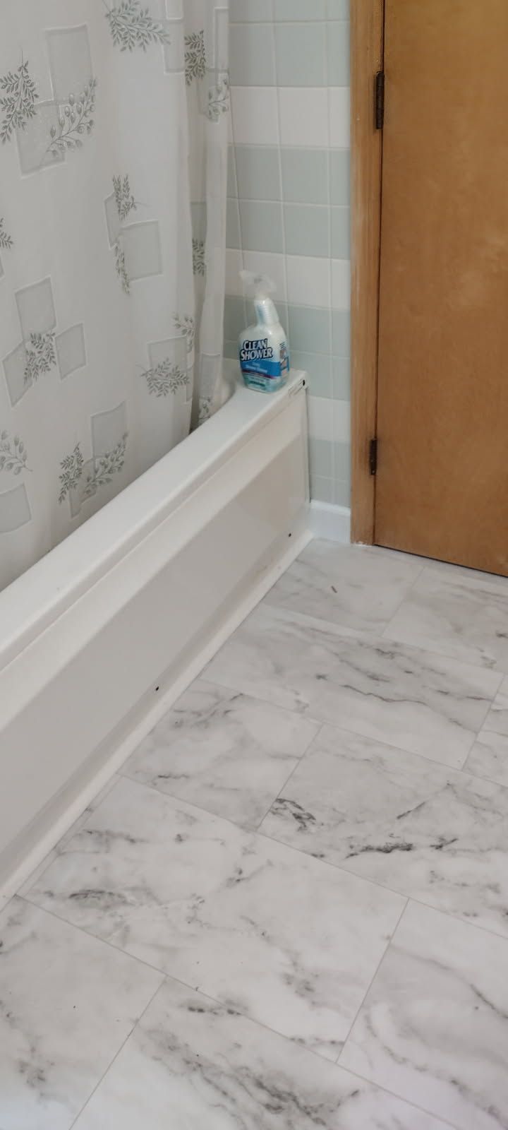 A bathroom with a marble floor and a shower curtain.