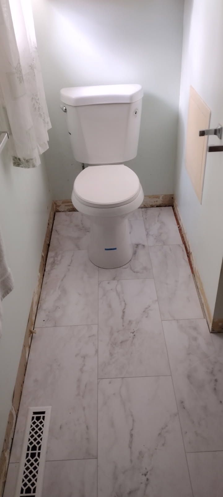 A toilet is sitting on a tiled floor in a bathroom.