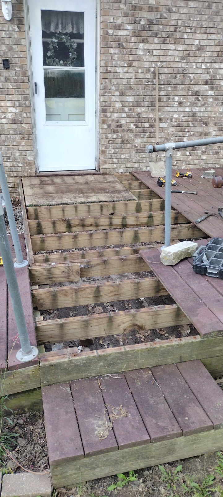 A wooden deck is being built in front of a brick house.