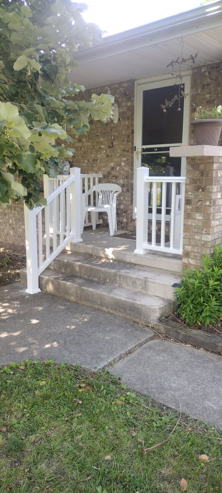 There is a porch with a white railing and stairs leading up to it.