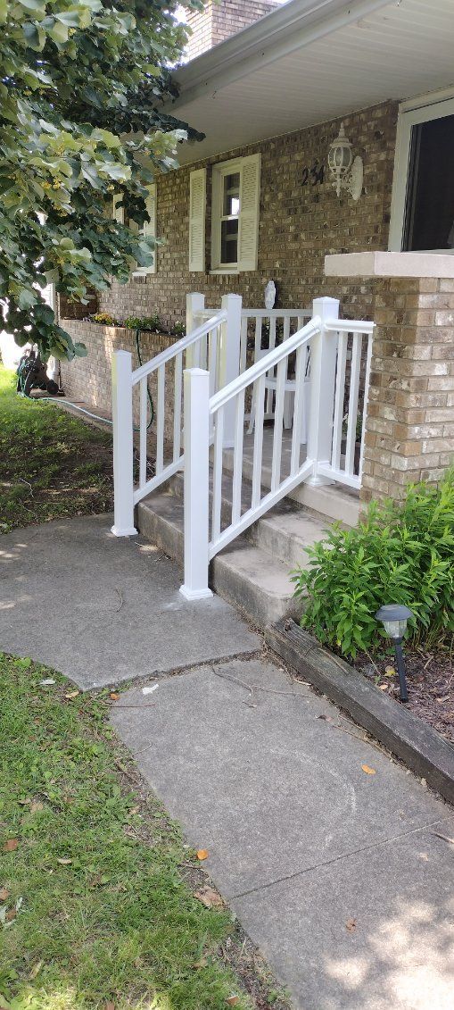 There is a white railing on the steps of a house.