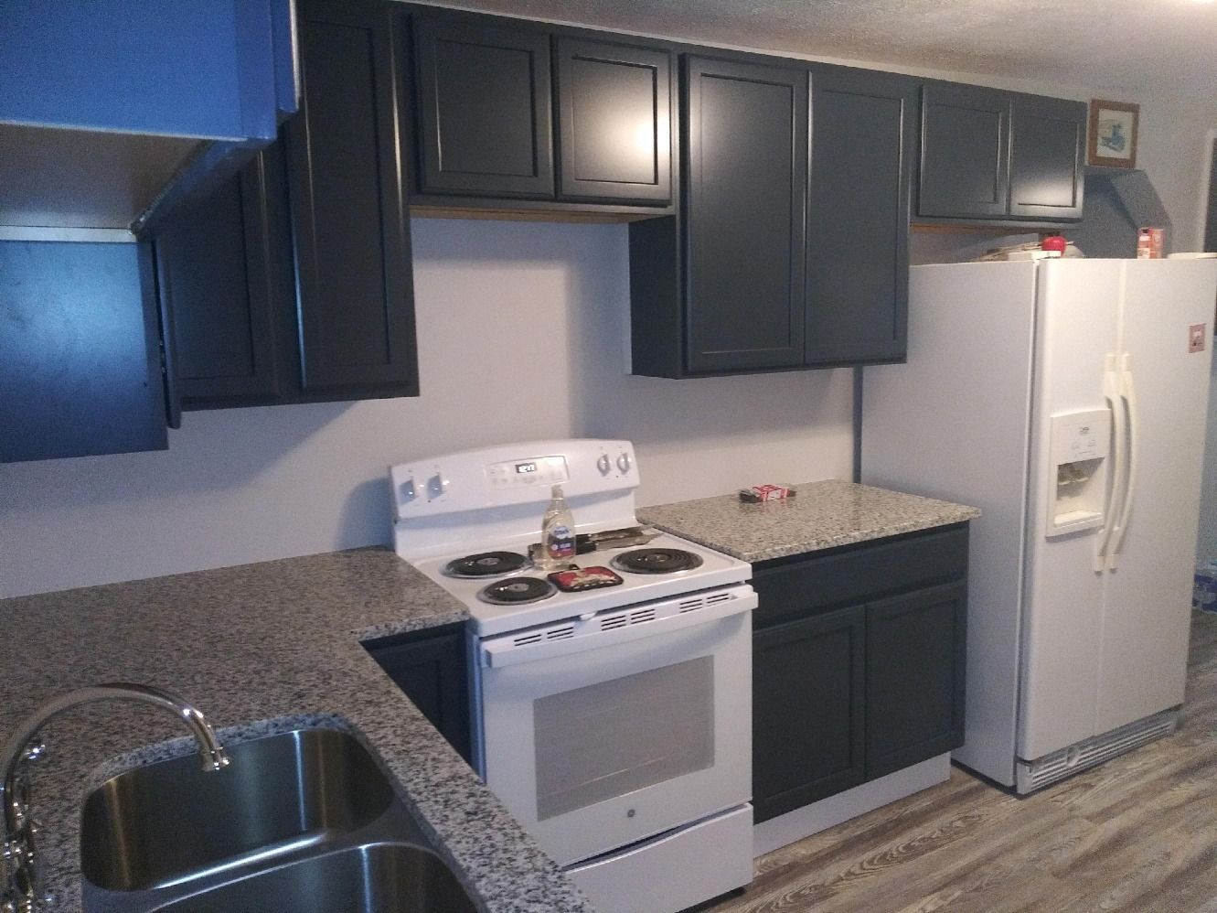 A kitchen with a stove , refrigerator , sink and cabinets.
