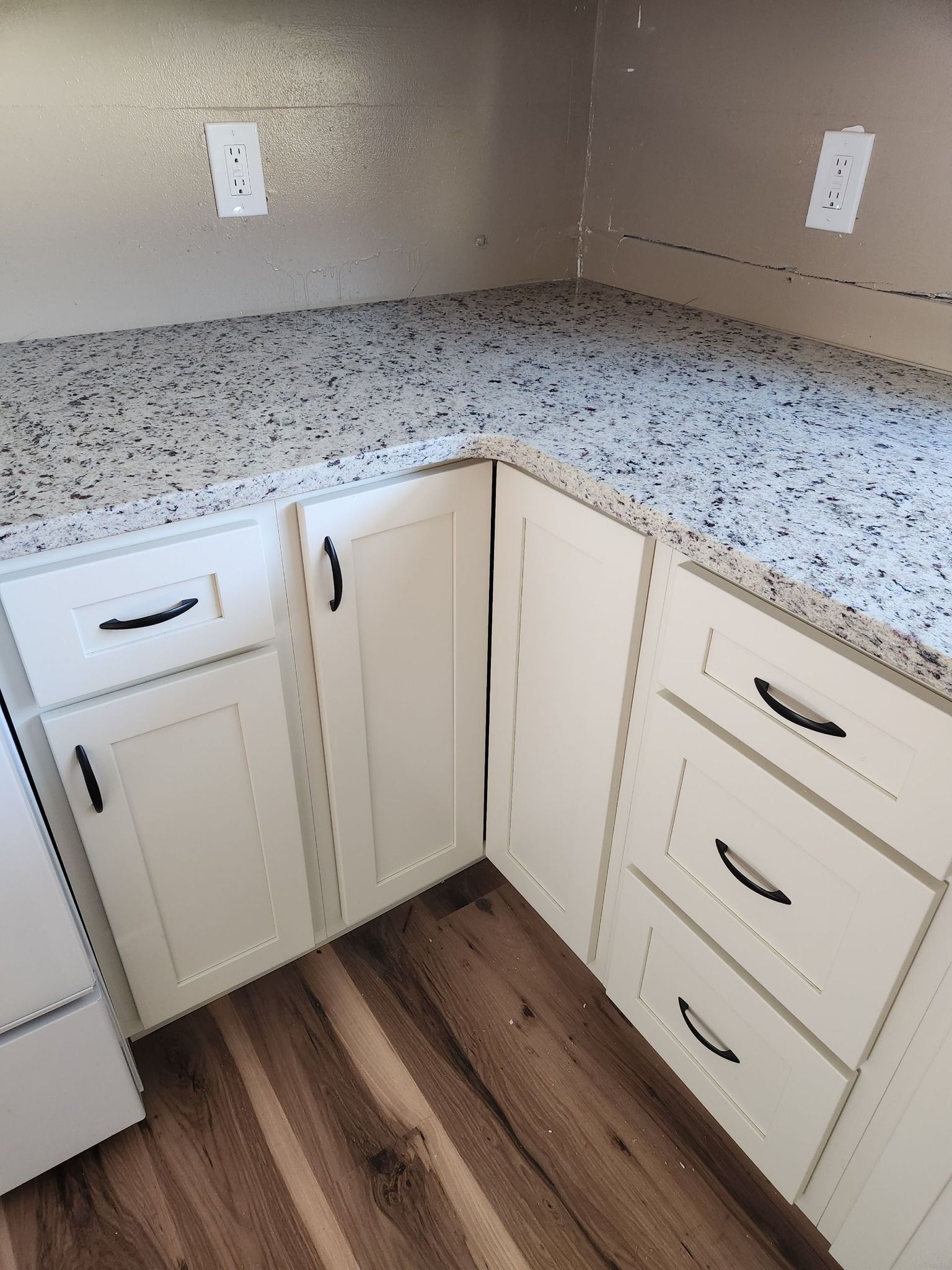 A kitchen with white cabinets and granite counter tops.
