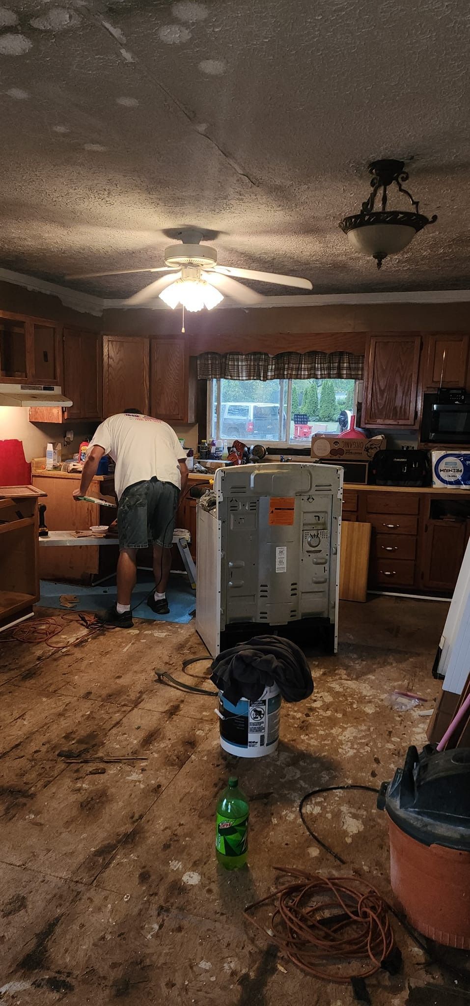 A man is working on a refrigerator in a kitchen.