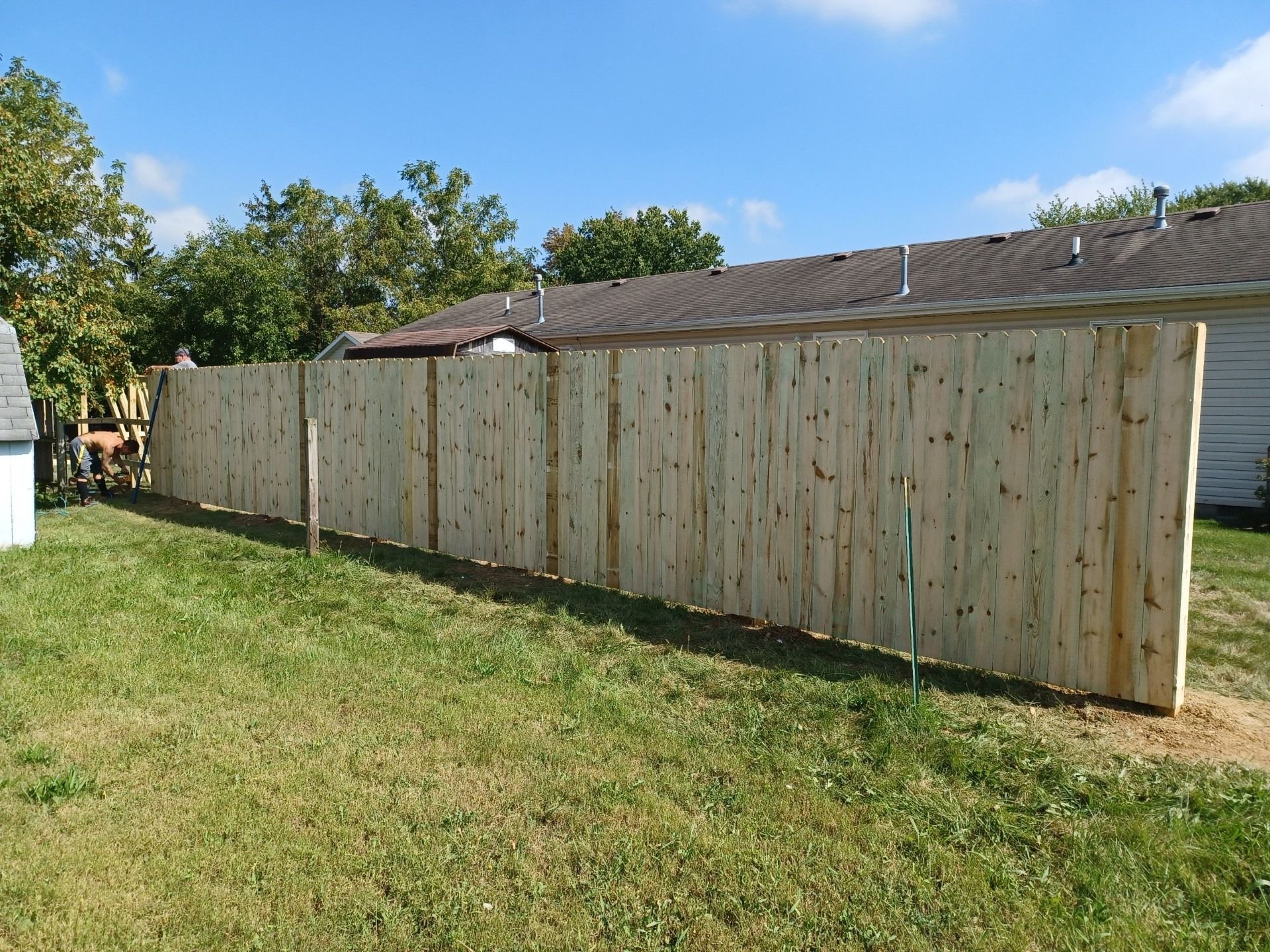 A wooden fence is sitting in the grass in front of a house.