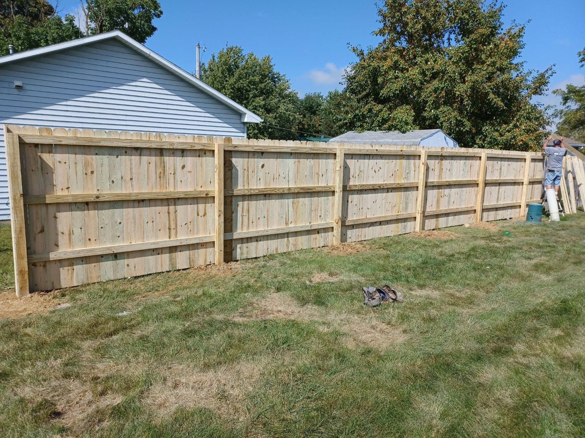 A wooden fence is being built in the backyard of a house.
