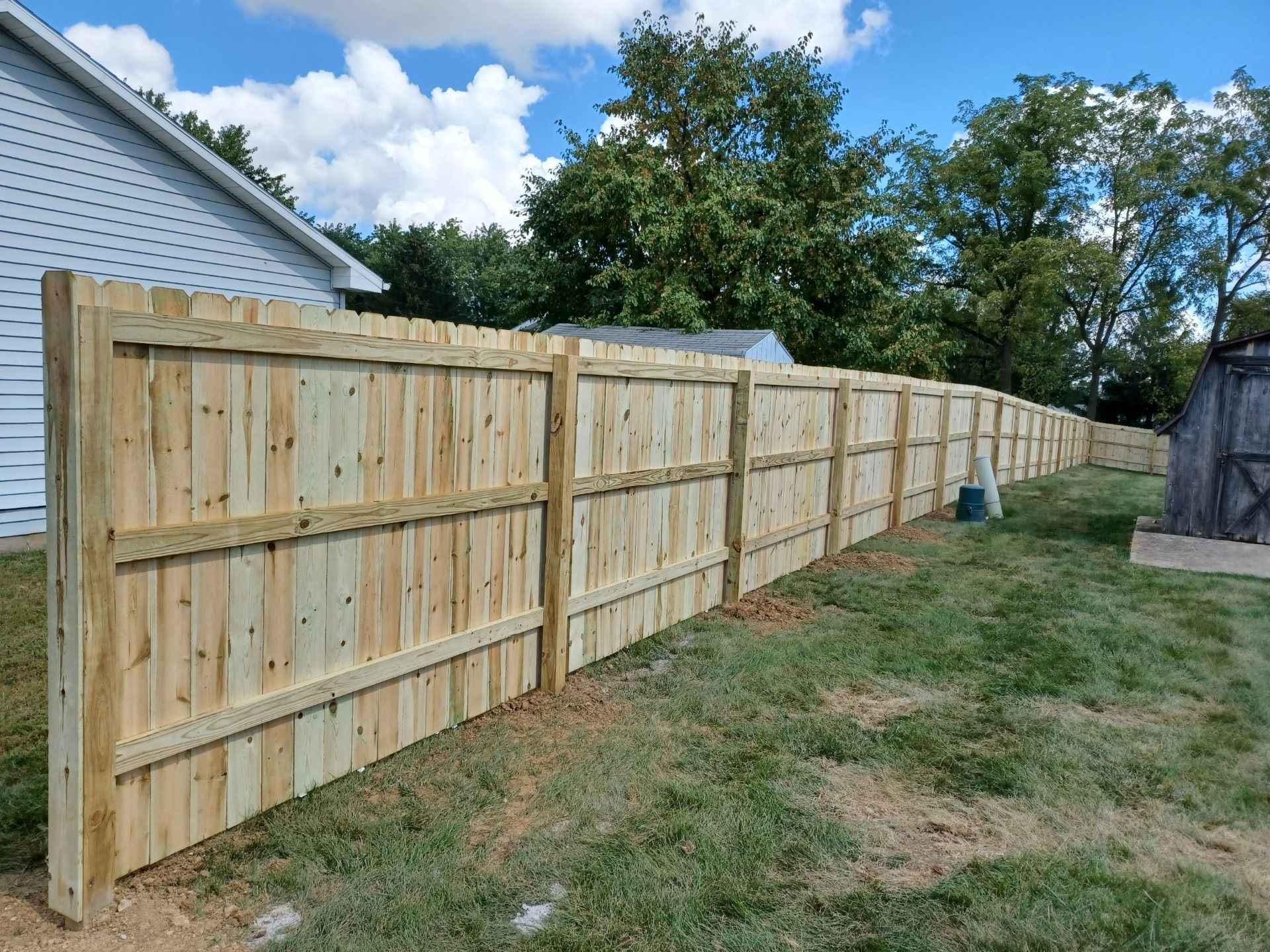 A wooden fence is sitting in the grass in front of a house.