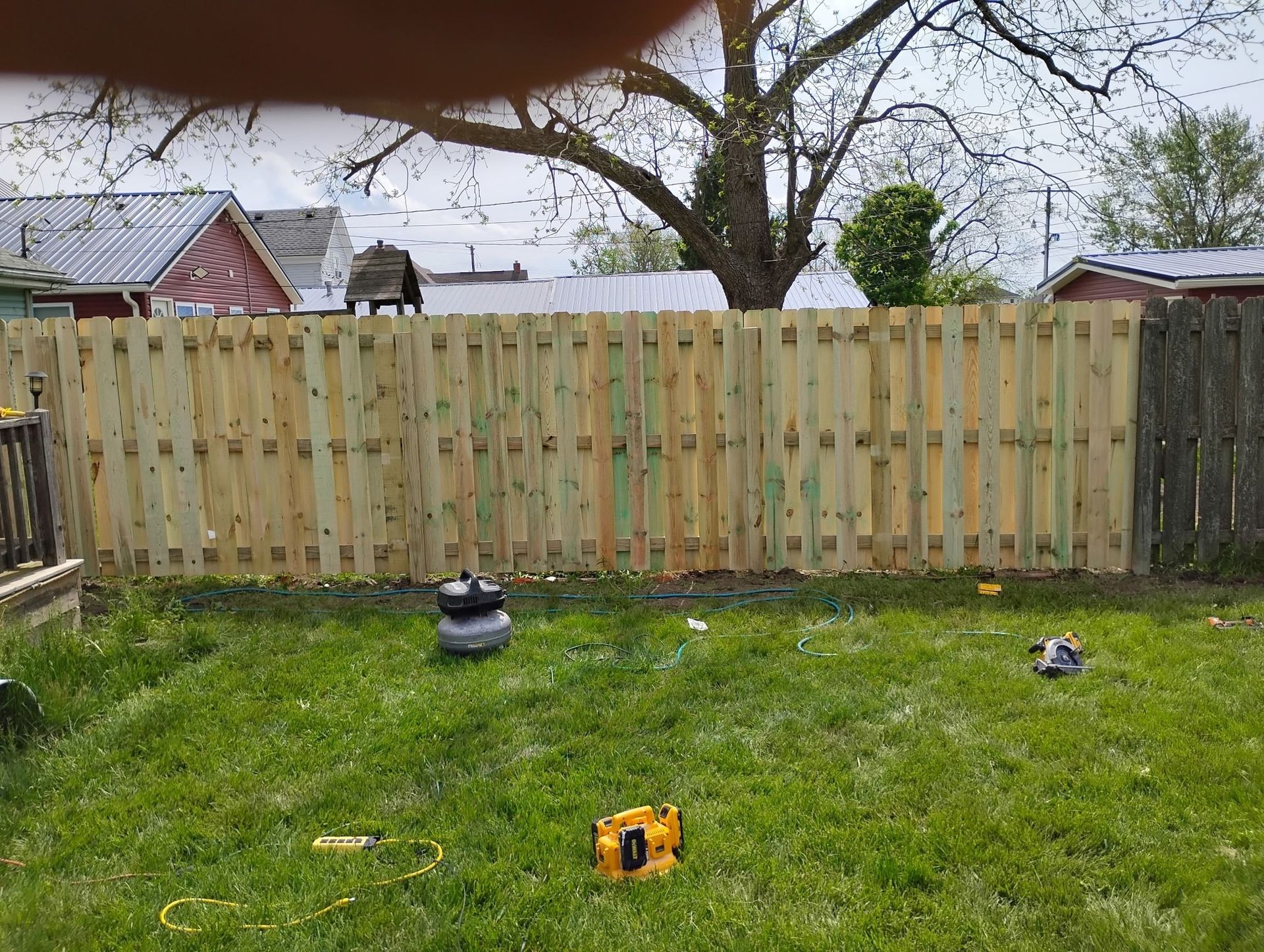 A wooden fence is being built in a backyard.
