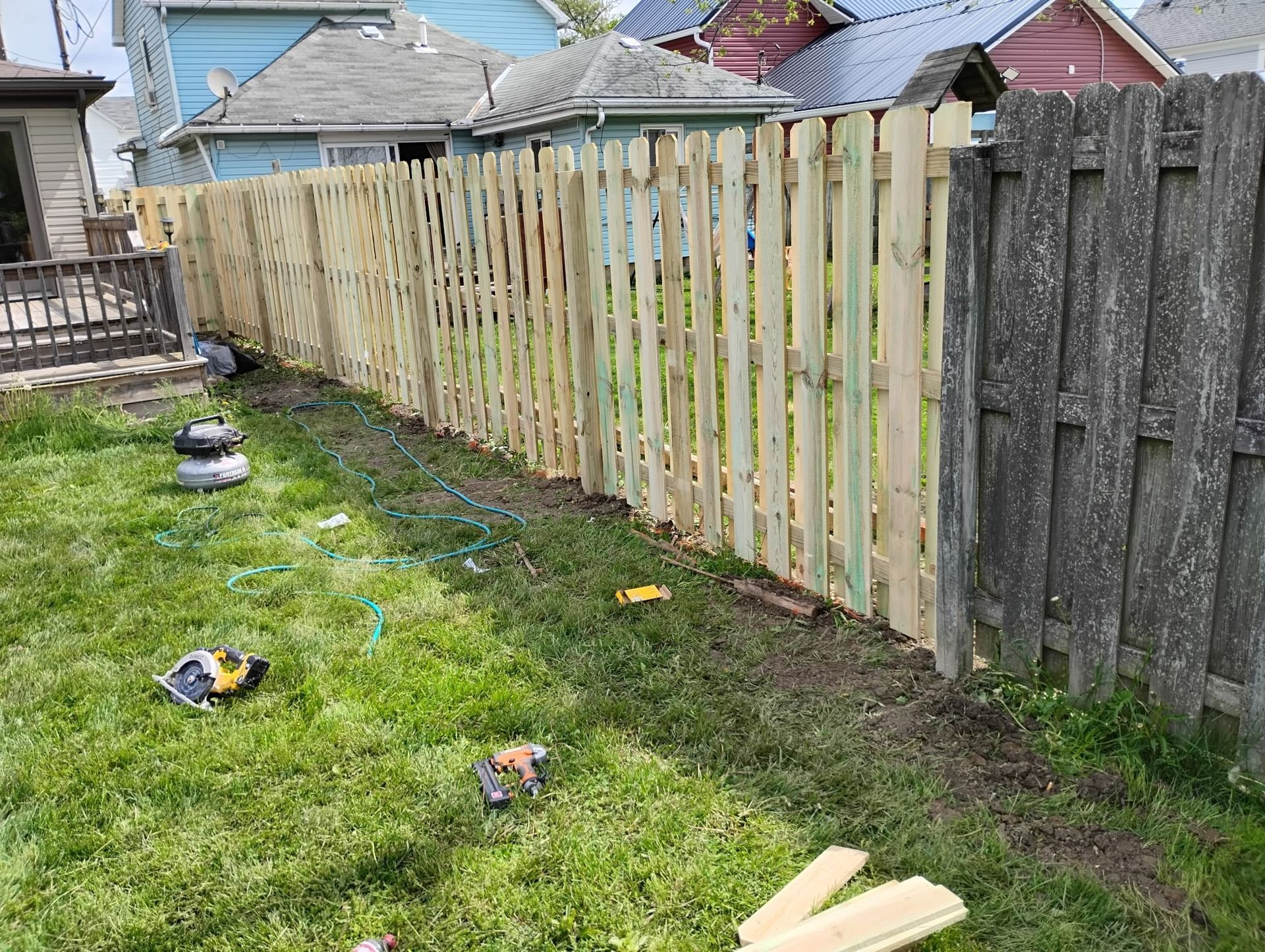 A wooden fence is being built in a backyard.