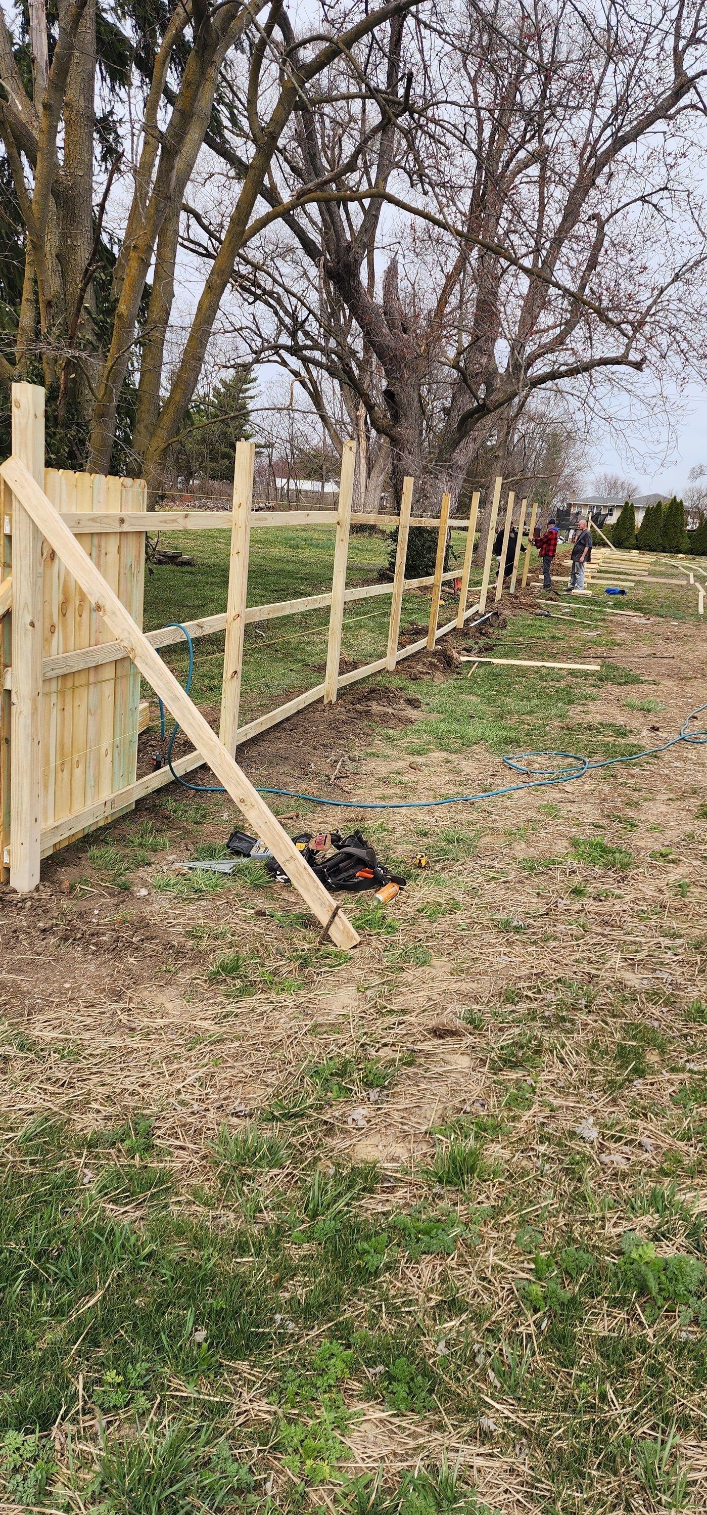 A wooden fence is sitting in the middle of a grassy field.