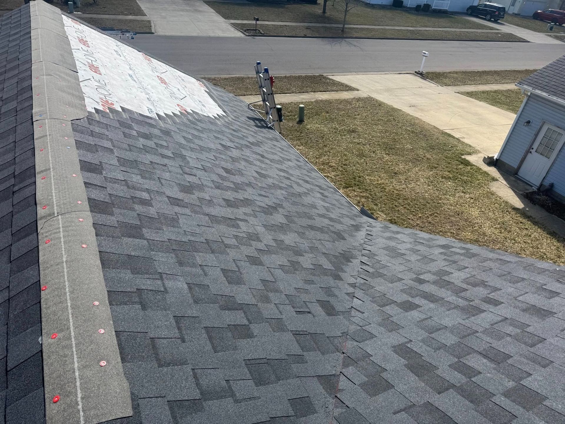 An aerial view of a roof with shingles being installed.