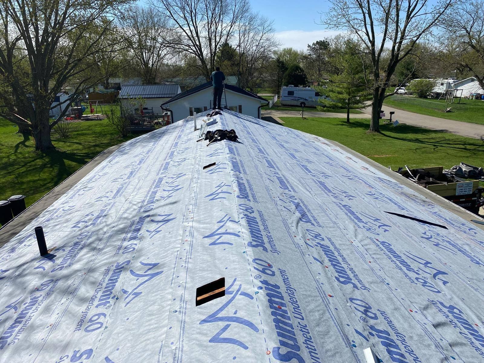 Two men are working on the roof of a white house.