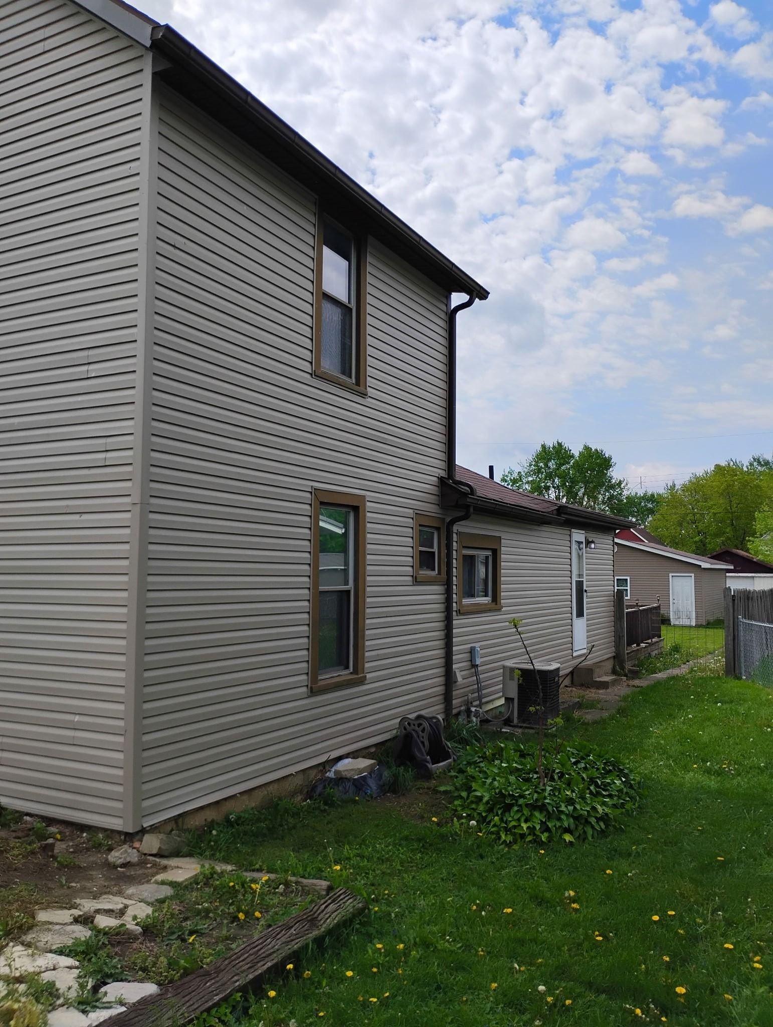 A house with a lot of windows is sitting in the middle of a lush green yard.