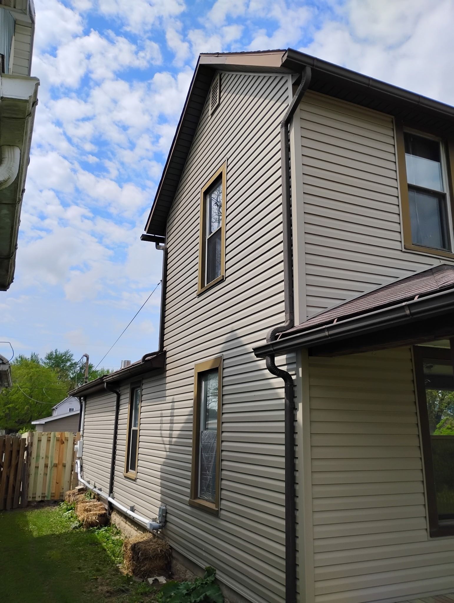 A house with a lot of windows and a porch is sitting in the middle of a grassy field.