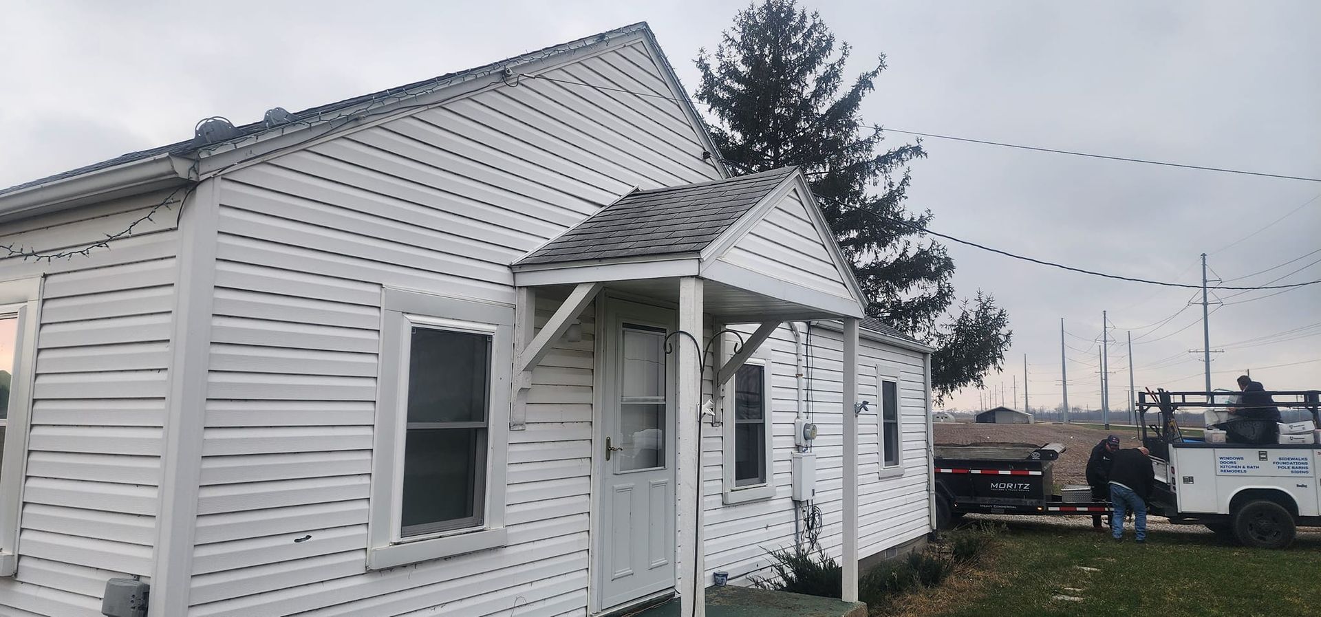 A white house with a porch and a truck parked in front of it.