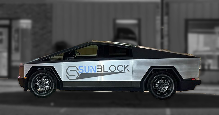 A silver Tesla Cybertruck is parked in front of a building.