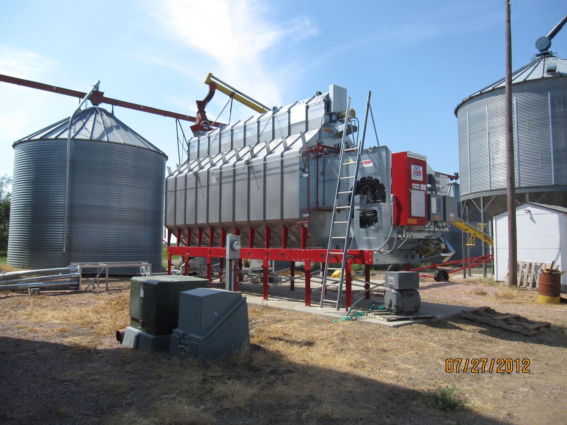 A large machine is sitting in front of a row of silos.
