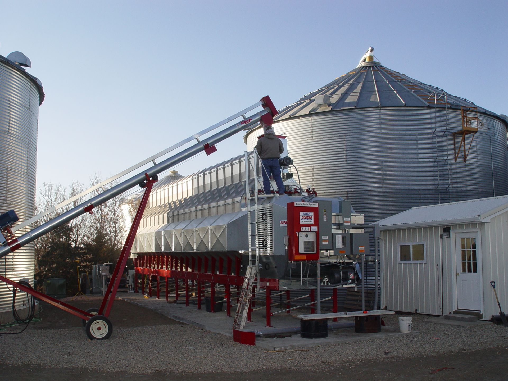 A man stands on a ladder in front of a silo that says ' a ' on it