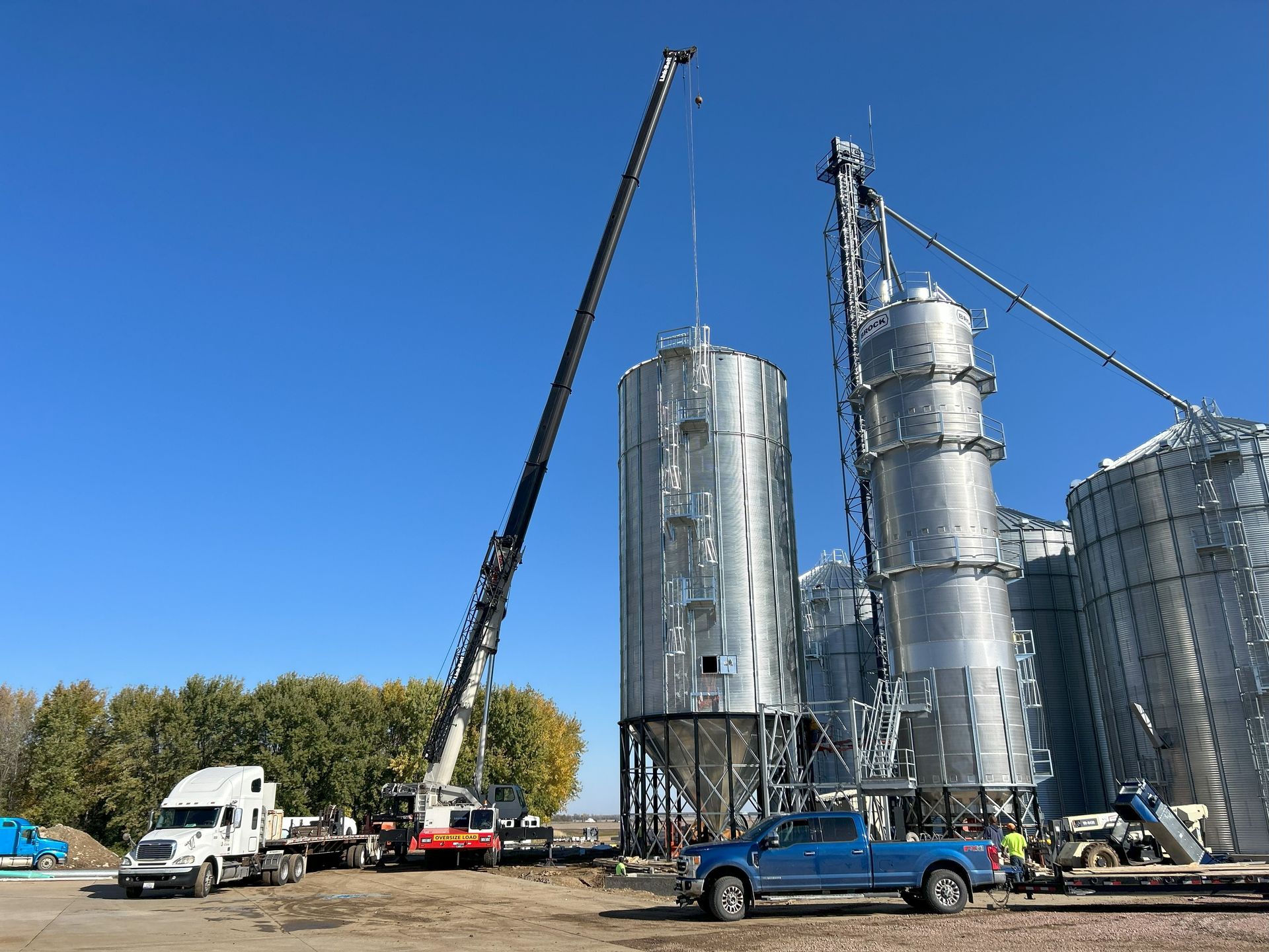 A truck is parked in front of a warehouse with a crane in the background.