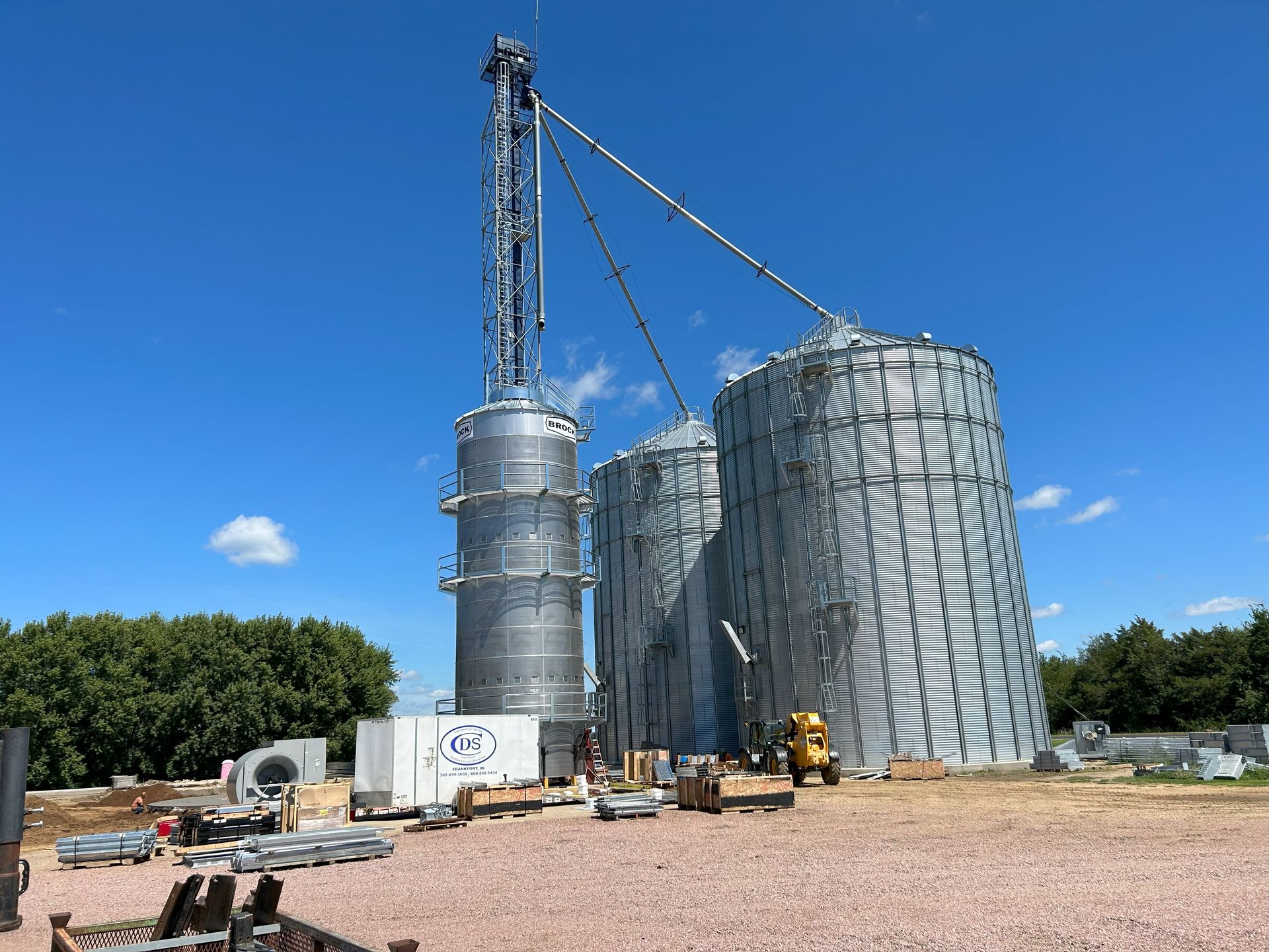 A row of silos are being built on a farm on a sunny day.