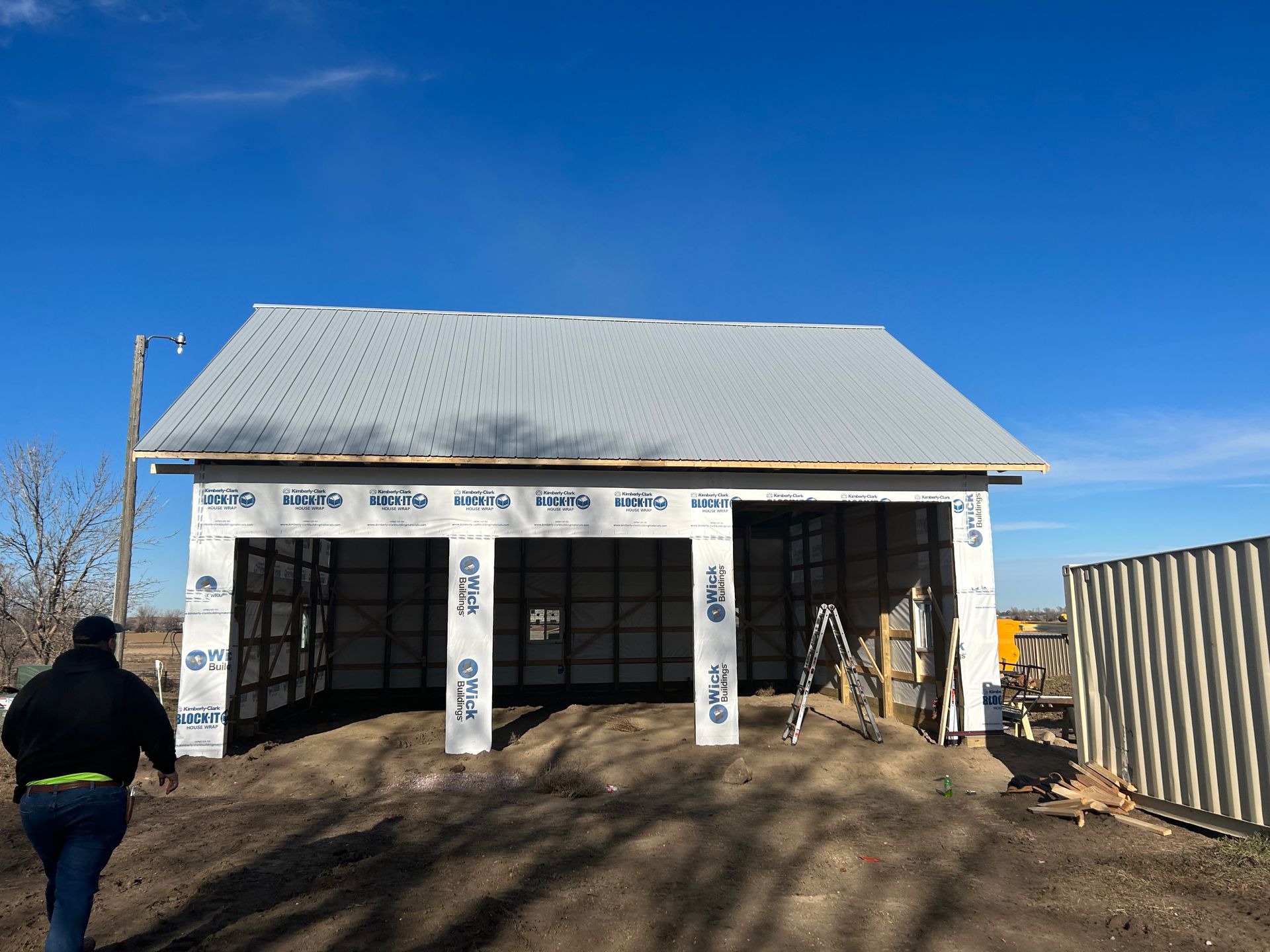 A man is walking in front of a garage under construction