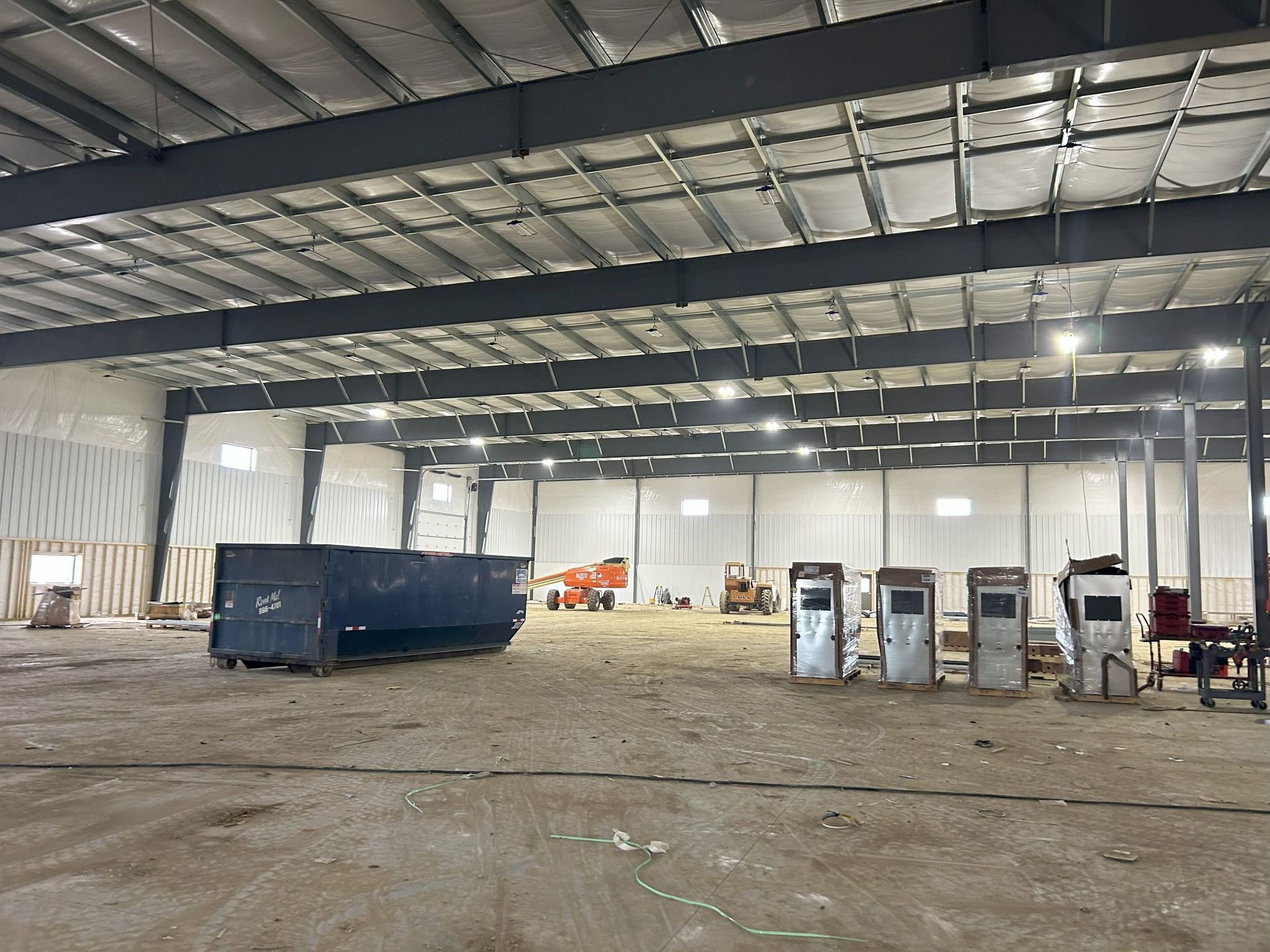 A large warehouse with a dumpster in the middle of it.