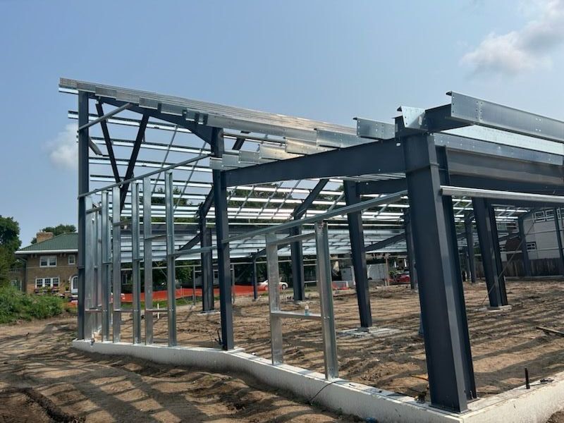 A large metal structure is being built in a dirt field.