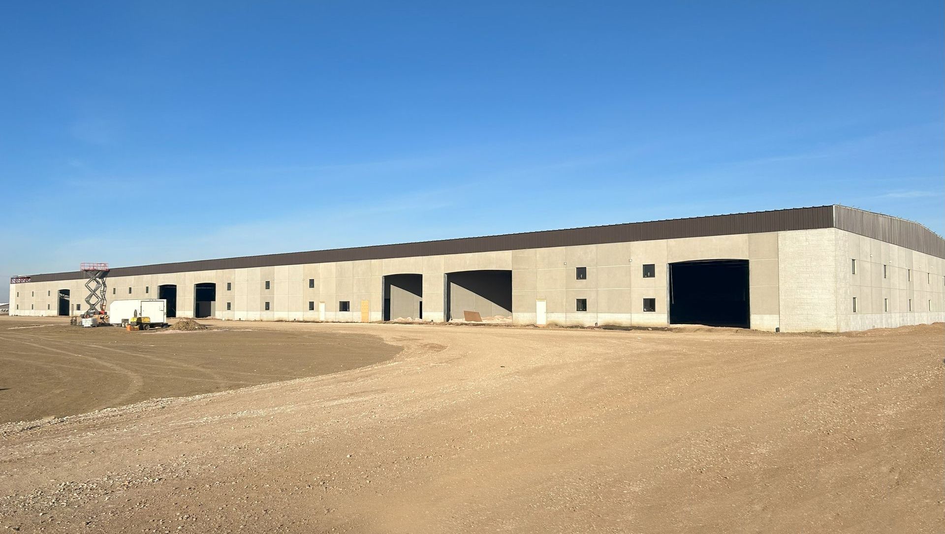 A large building is being built in the middle of a dirt field