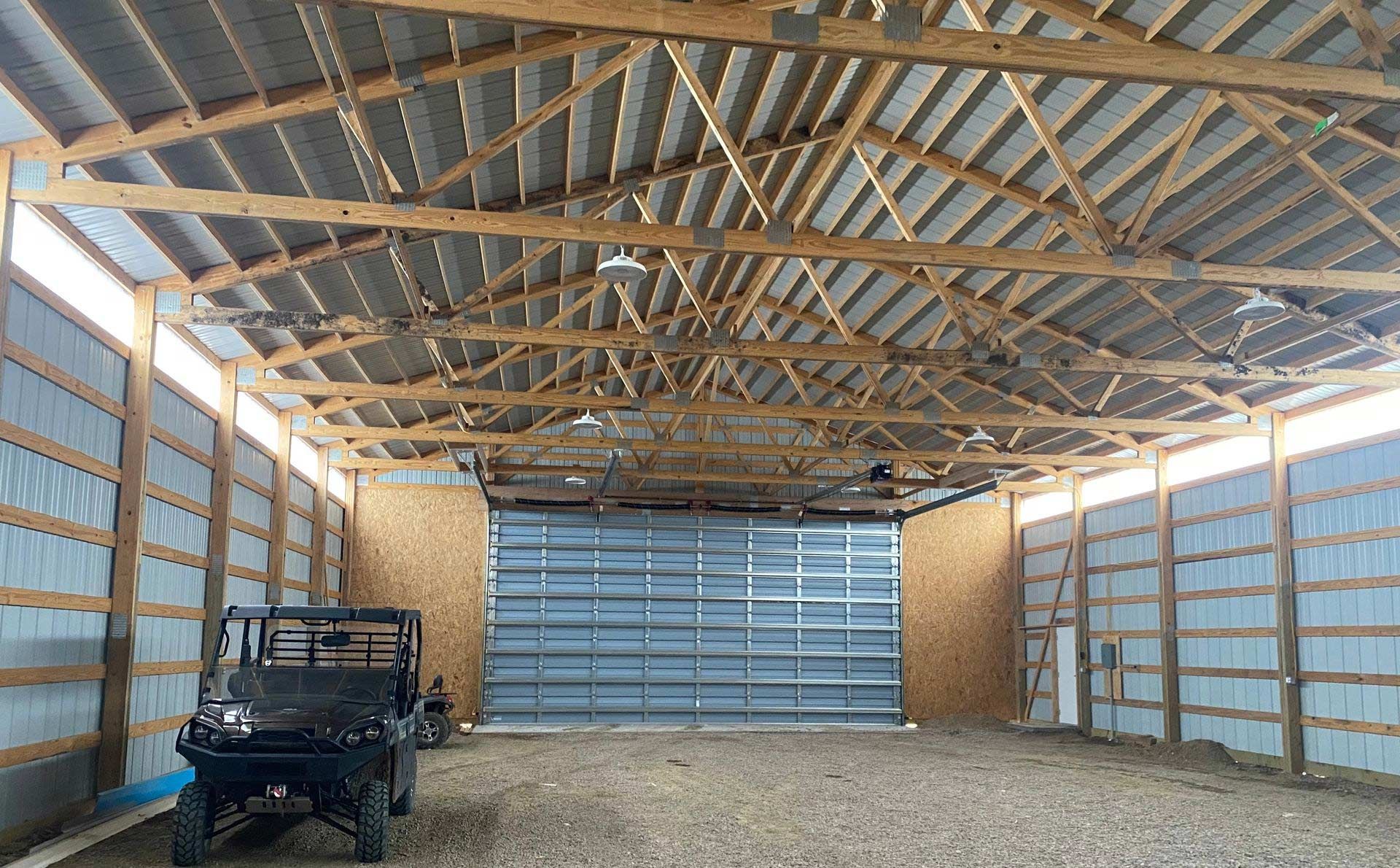 A vehicle is parked inside of a garage with a large garage door.