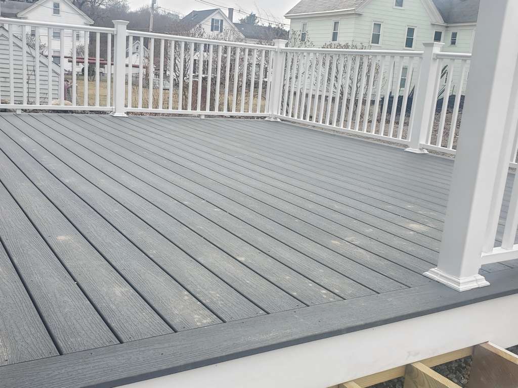 Gray composite deck with white railing, overlooking neighboring houses.