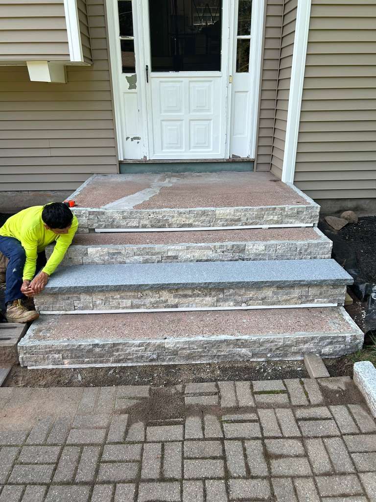 Worker repairing concrete front steps at a house entrance