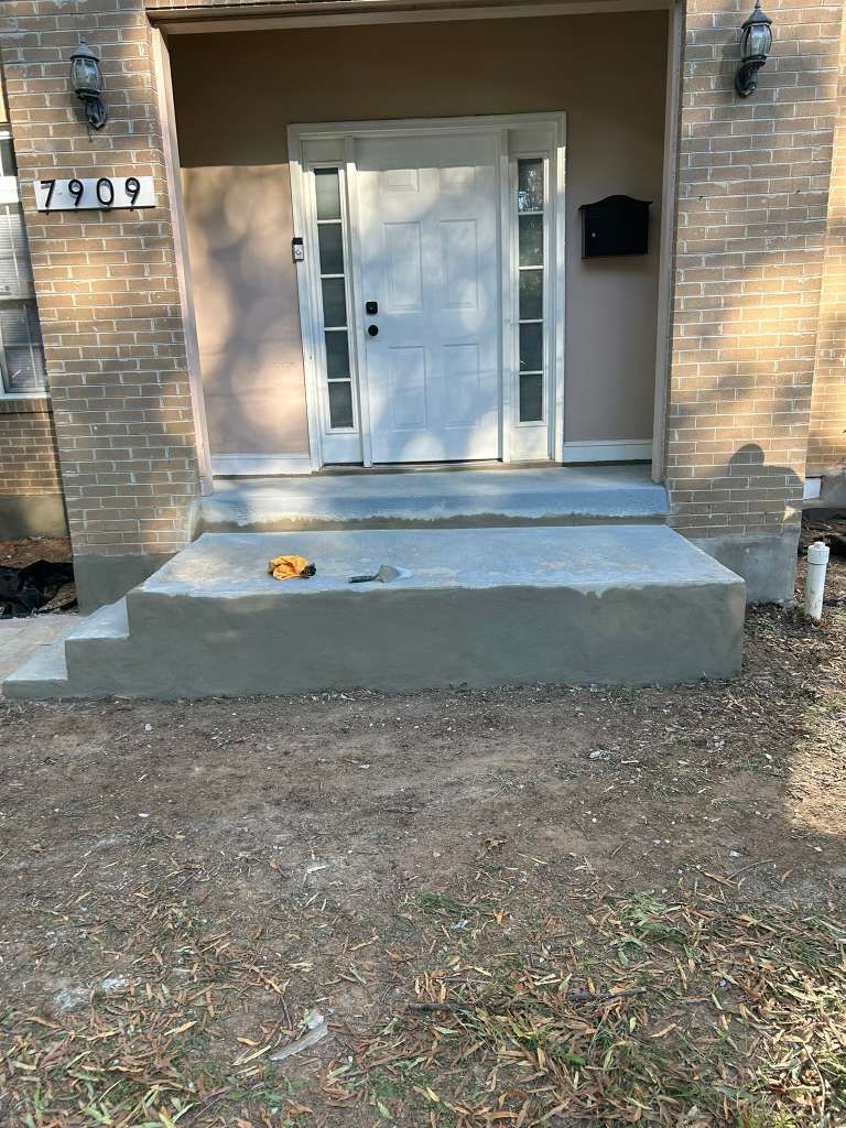 Brick house front porch with concrete steps, white door, and a small object on the porch.