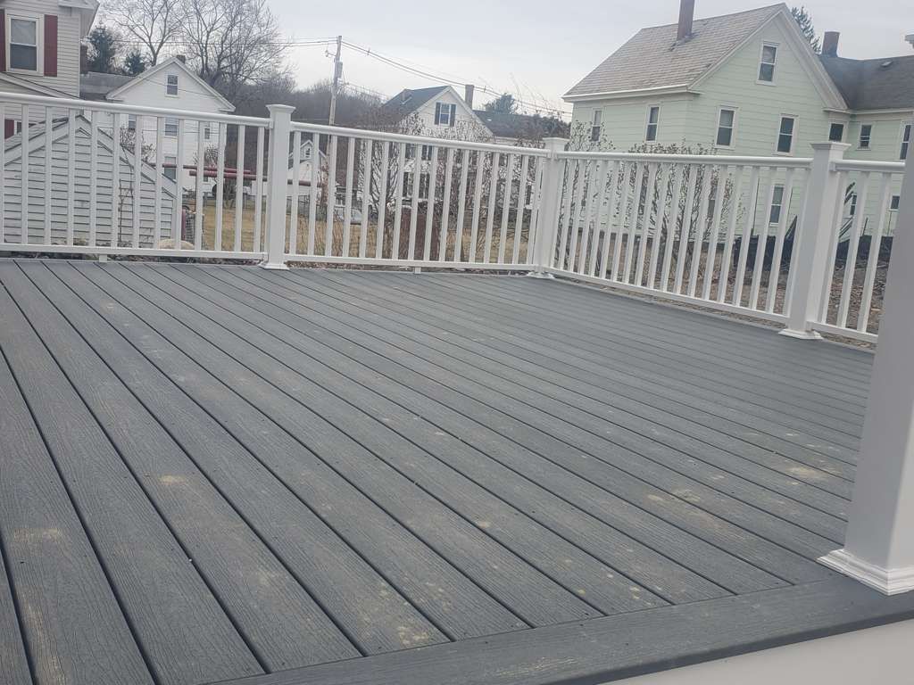 Empty gray deck with white railings overlooking neighboring houses