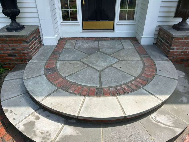 Front porch with a curved brick-and-stone step and round stone landing by a black front door