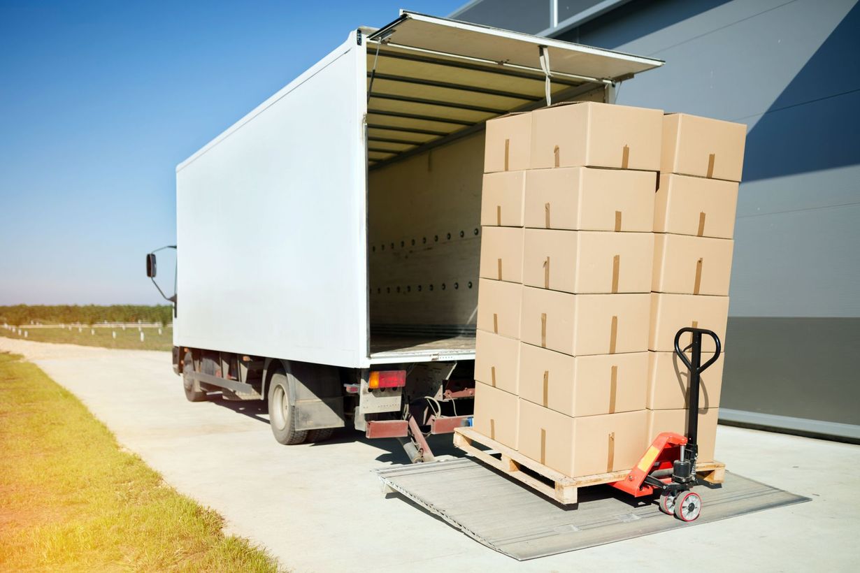 Box truck being unloaded with stacked cardboard boxes on a pallet at a warehouse loading dock