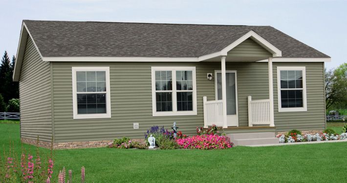 A small green house with a gray roof is sitting on top of a lush green field.