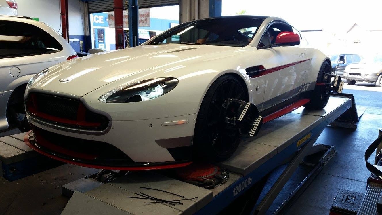 White race car with red and black accents on a dyno test platform in a garage
