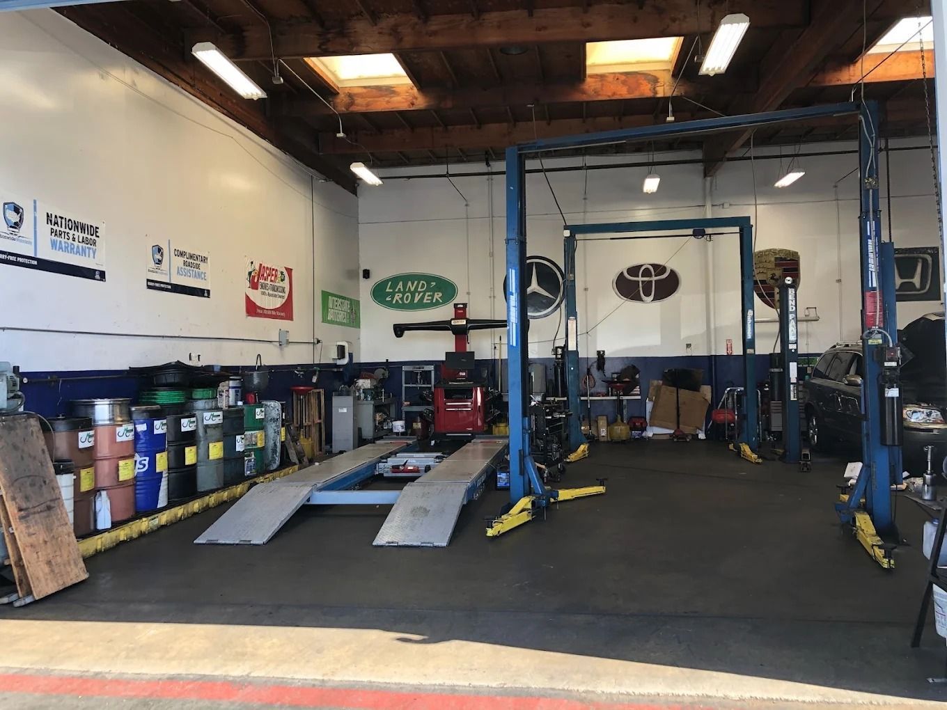 Auto repair shop with car lifts, ramps, tires, and service equipment inside a garage