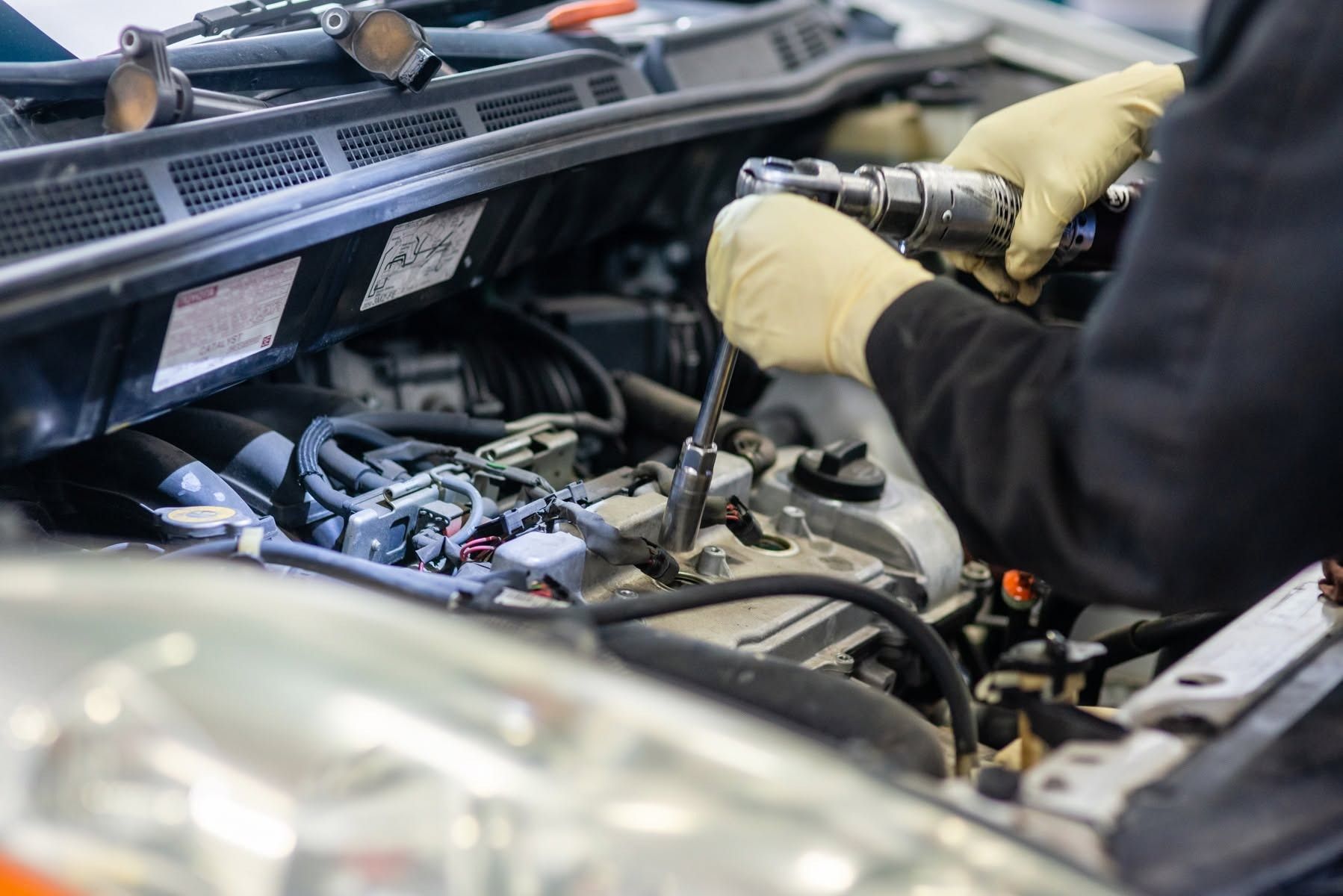 Mechanic using a wrench to work on a car engine under the hood