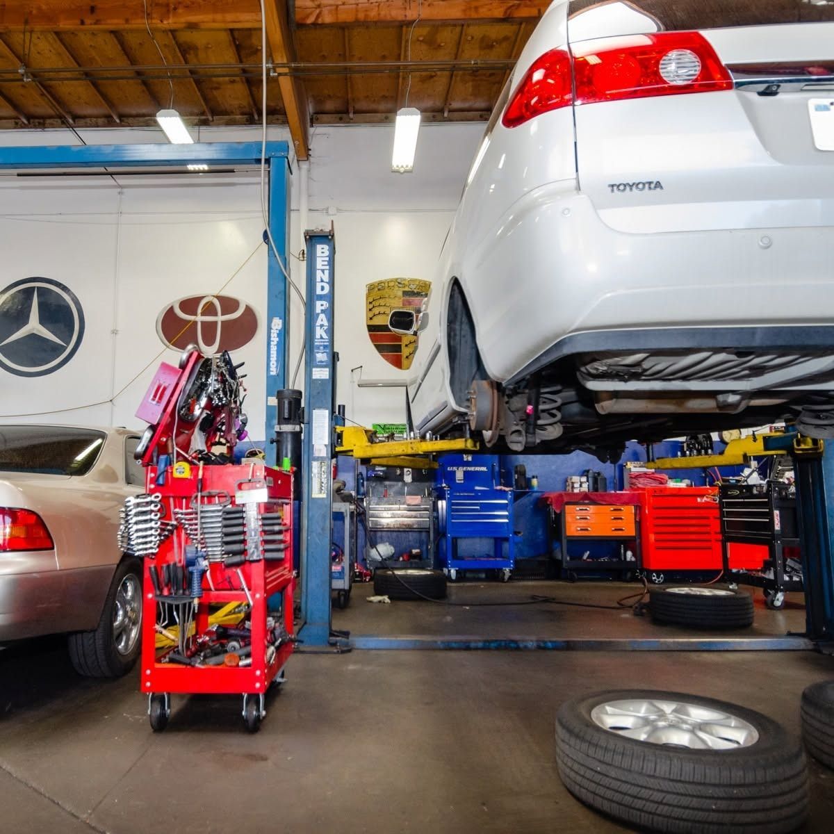Auto repair shop with cars on lifts, tool carts, and a spare tire on the floor