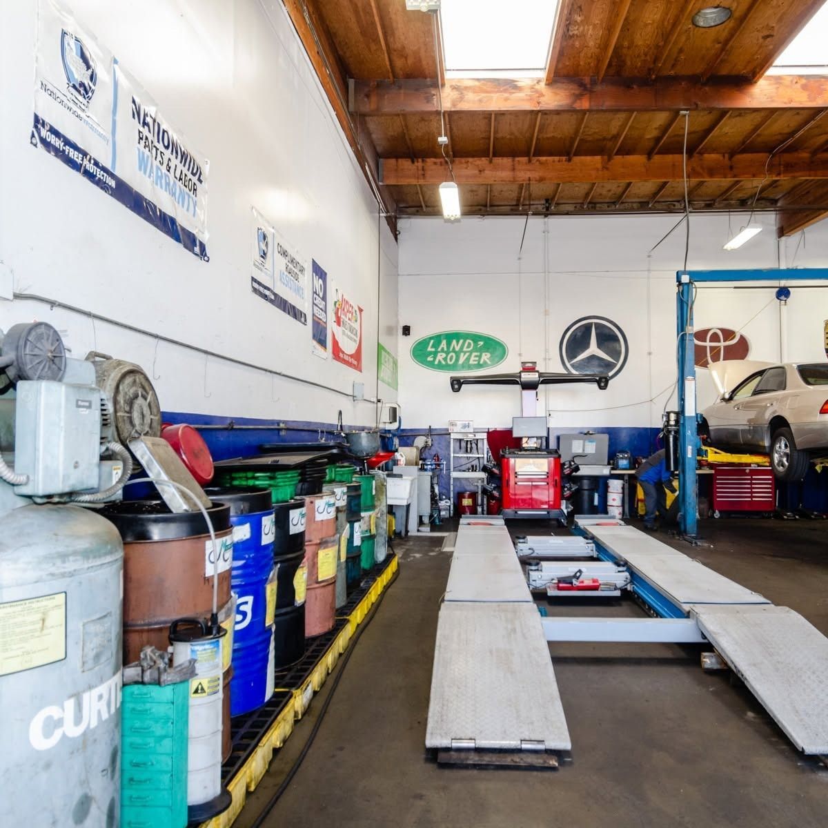 Auto repair shop interior with car lift, tools, oil drums, and vehicles in service bays