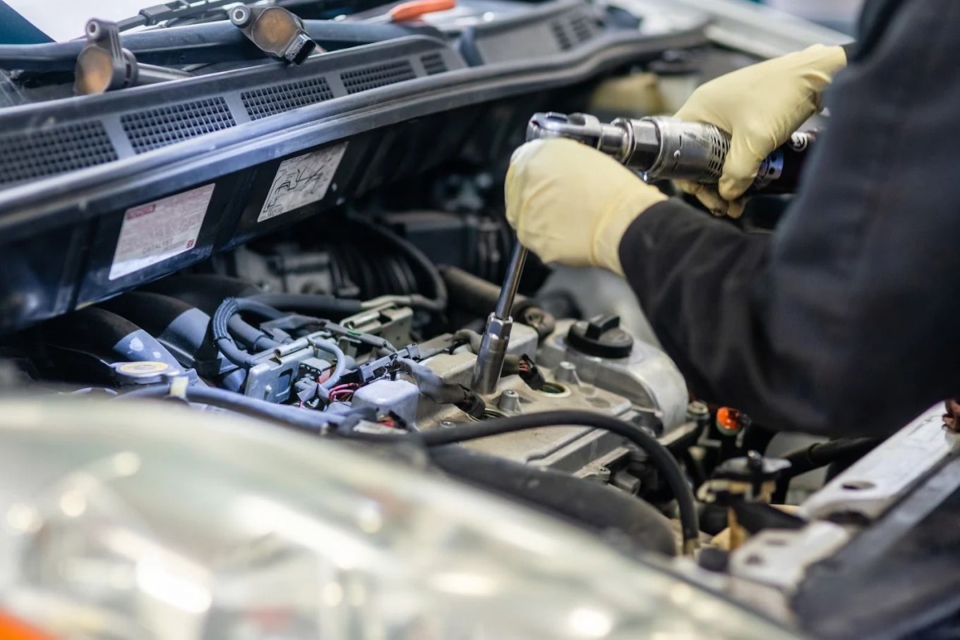 Mechanic using a ratchet wrench to repair a car engine under the hood