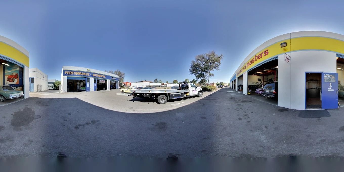 Wide-angle view of a sunny car repair shop with a white pickup truck and open service bays