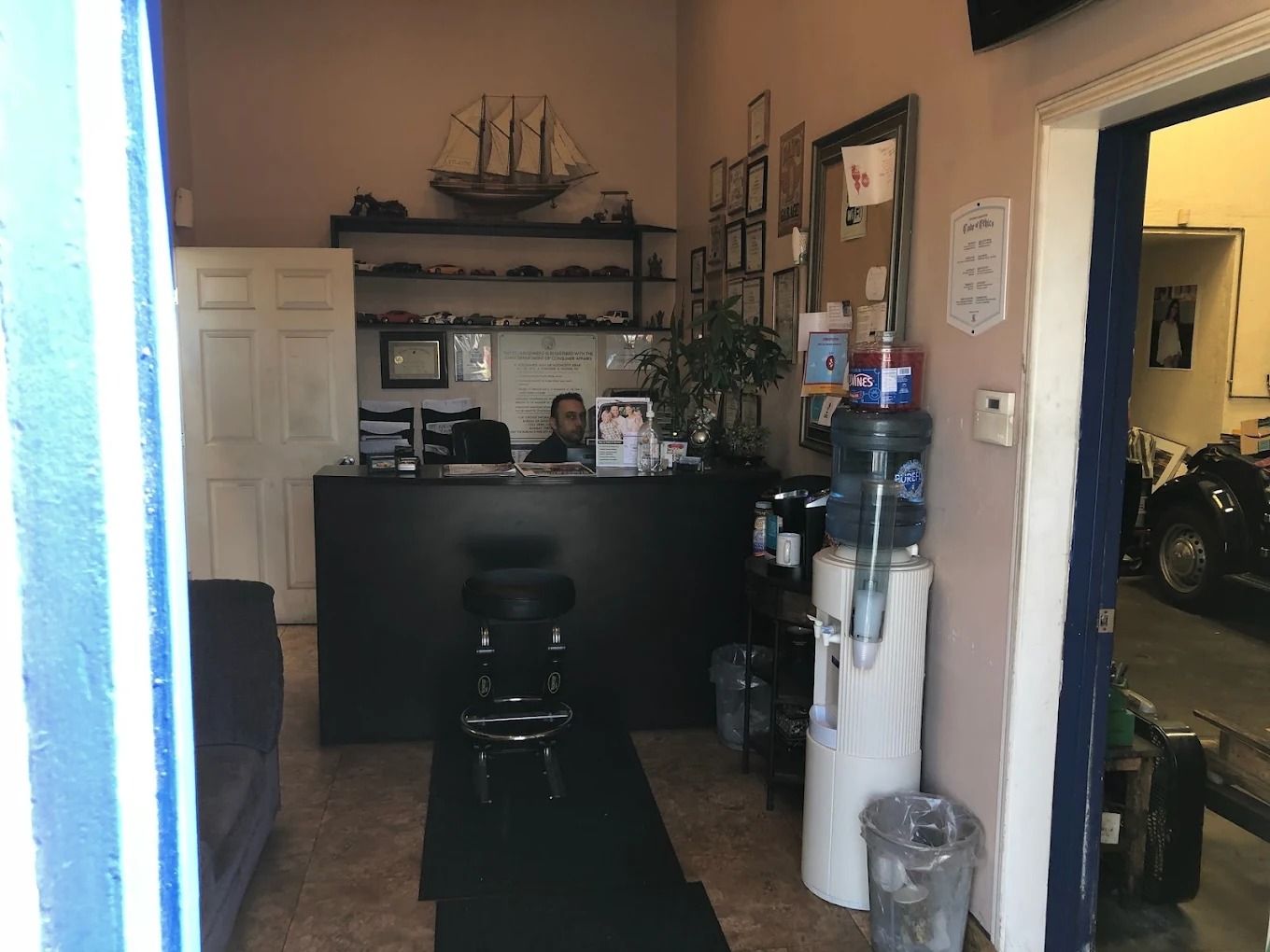 Small home bar area with a black counter, stool, shelves, and a doorway to a garage on the right.